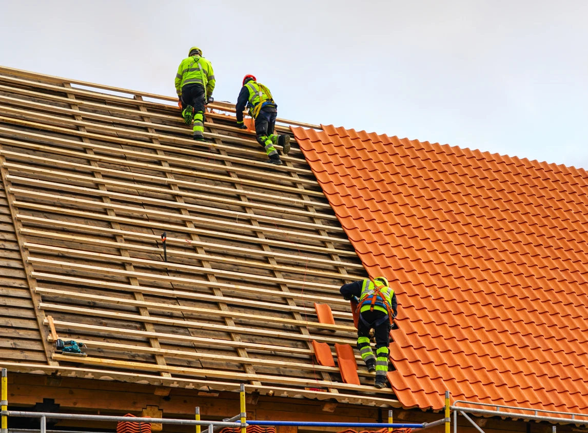 Construction workers installing roof tiles